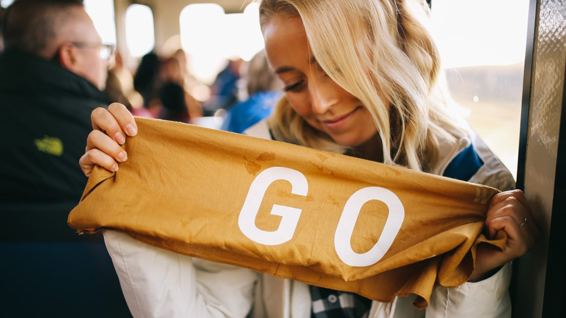 Junge Frau hält eine Flagge mit der Aufschrift GO für die Jack Wolfskin Kampagne #GOBACKPACK