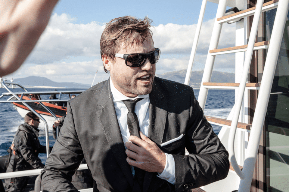 Mann im schwarzen Anzug steht auf einem Segelboot für die Hugo Boss Social Media Kampagne