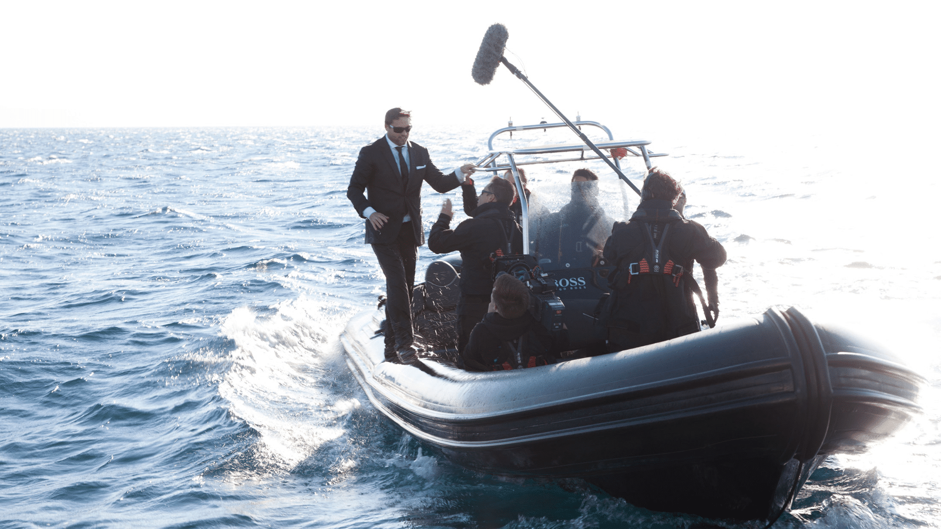 Mann im schwarzen Anzug und Kamerateam auf einem Schlauchboot für die Hugo Boss Social Media Kampagne