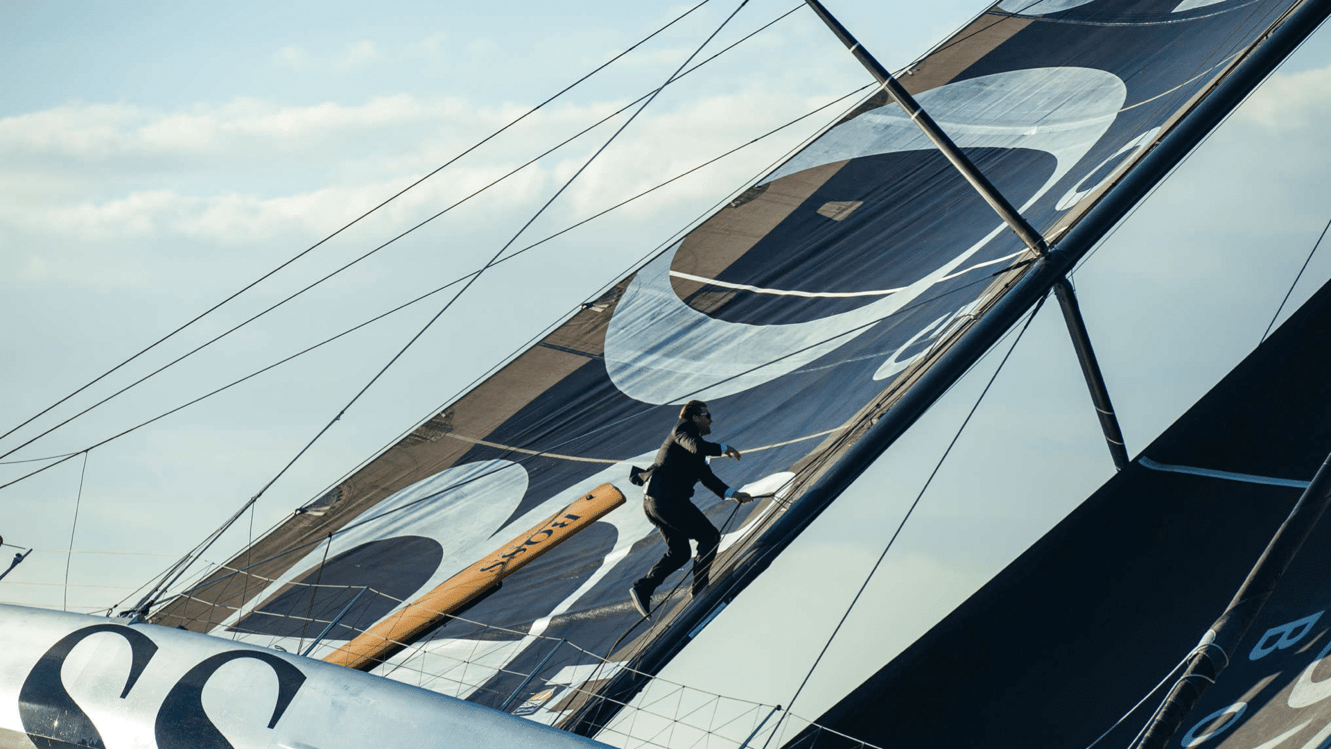 Mann im schwarzen Anzug läuft das Segel eines Segelbootes hoch für die Hugo Boss Social Media Kampagne