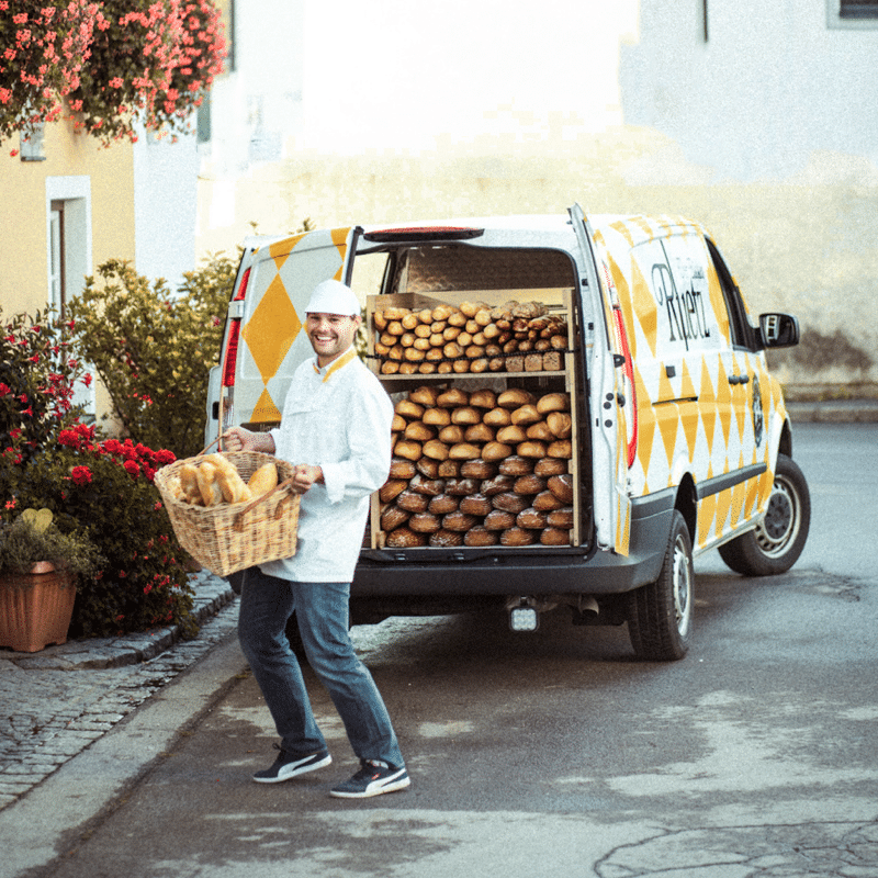 Ein Bäcker steht vor einem Transporter voller Brot und hält ein Korb mit Brot in der Hand für den Markenrelaunch der Bäckerei Ruetz